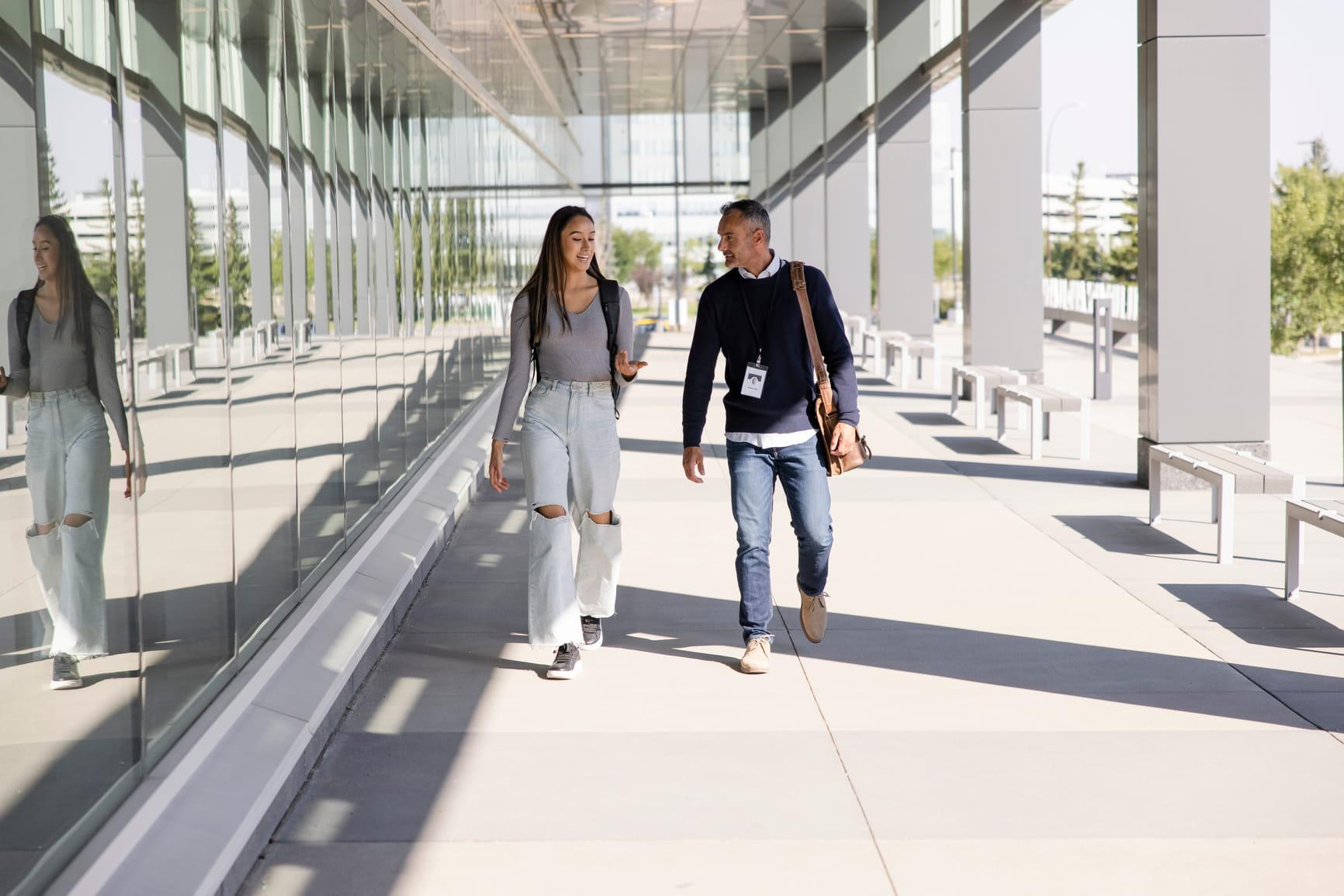 Twee mensen lopen op een trottoir en zijn in gesprek.