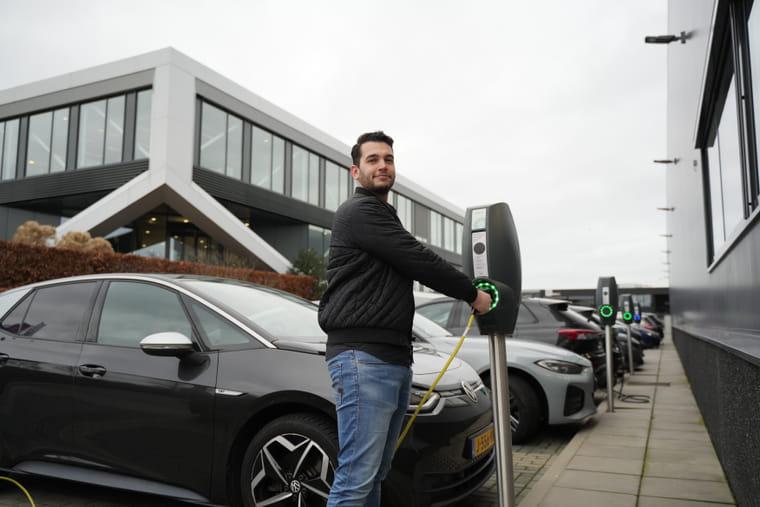 Man steekt de stekker van zijn elektrische auto in de oplaadpaal.