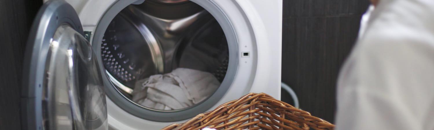 Persoon stop de was in een open wasmachine.