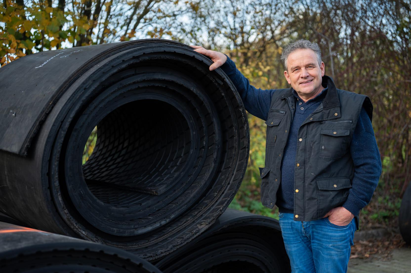 Boer staat buiten met rollen rubber.