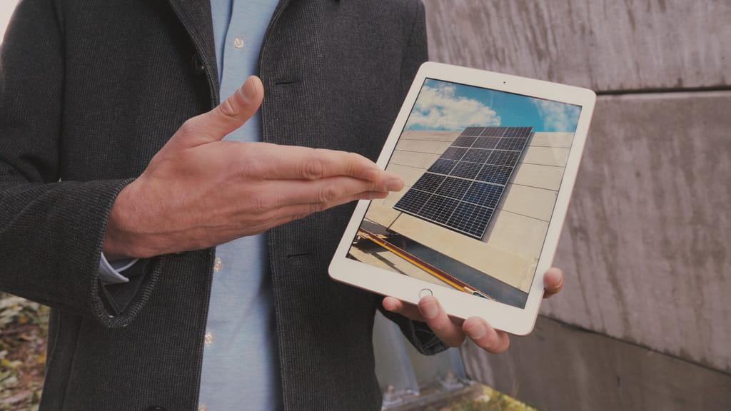 De hand van een man wijst naar een plaatje van een zonnepaneel op een tablet.