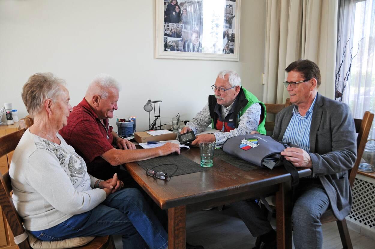 Er vindt een coachgesprek plaats over energiebesparing aan tafel. Er zitten vier mensen.