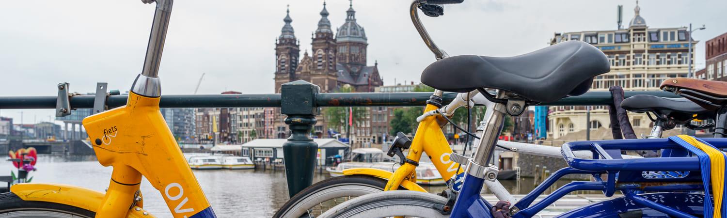 Foto van twee OV-fietsen die aan de reling van een brug staan geparkeerd.