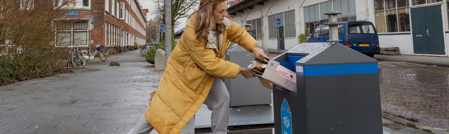 Vrouw gooit afval weg in een ondergrondse container.