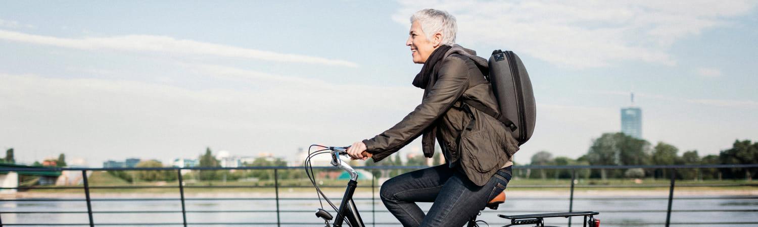 Een vrouw is op de fiets onderweg naar werk en fietst over een brug.