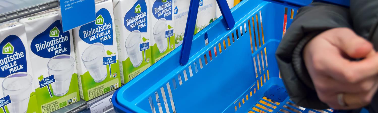 Foto van een boodschappenmandje in de Albert Heijn voor het schap met houdbare, biologische melk.