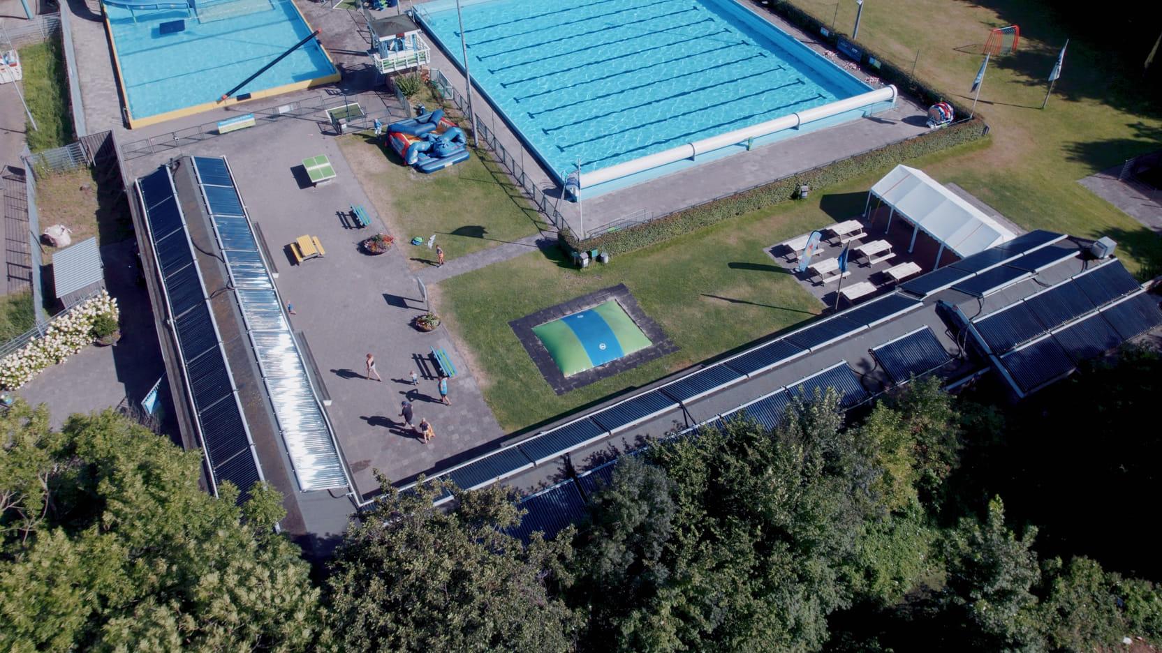 Luchtfoto van openluchtzwembad De Zien. Op de gebouwen zie je zonnepanelen.
