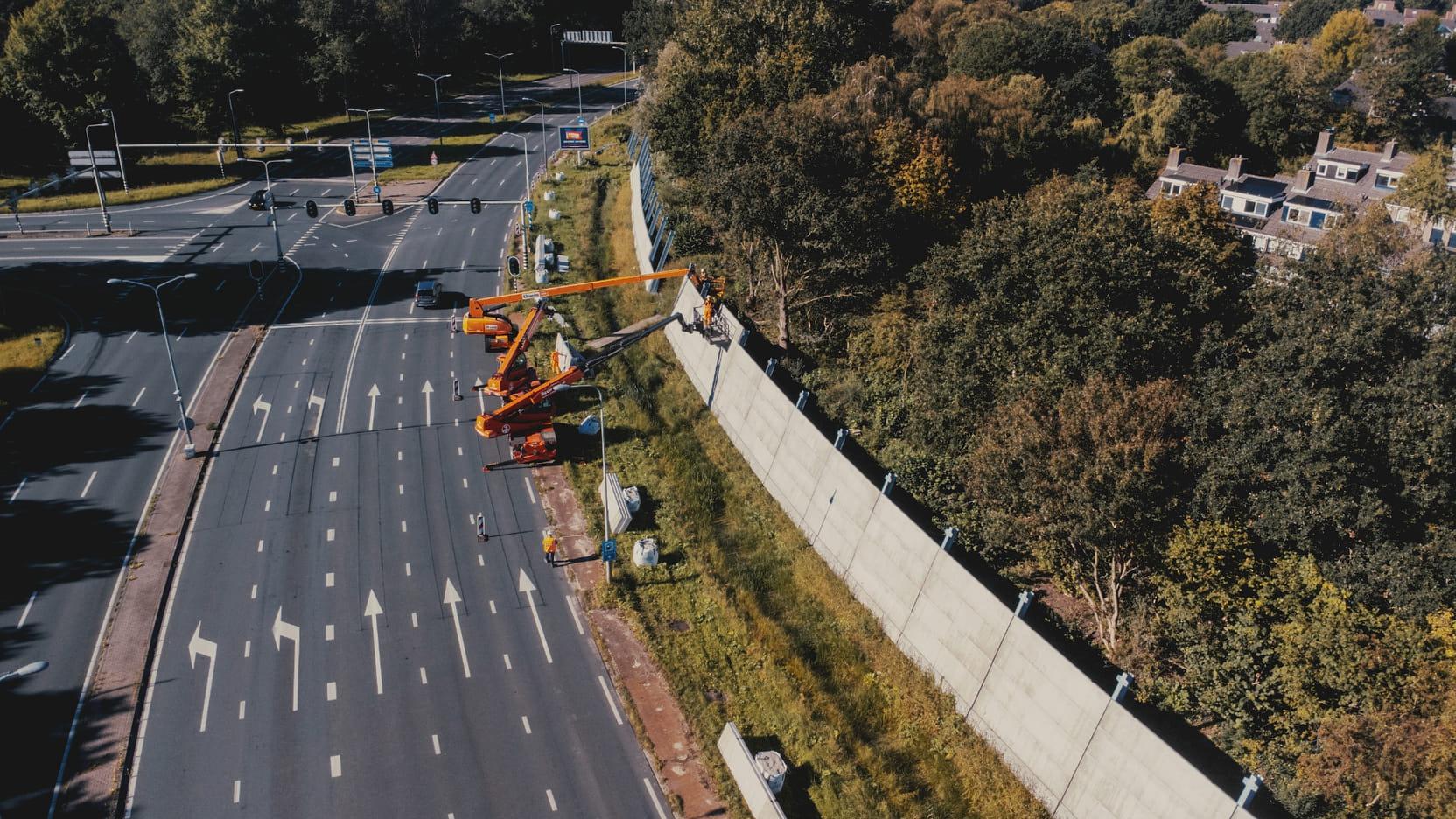 Luchtfoto van de installatie van geluidsweringsschermen langs de snelweg.
