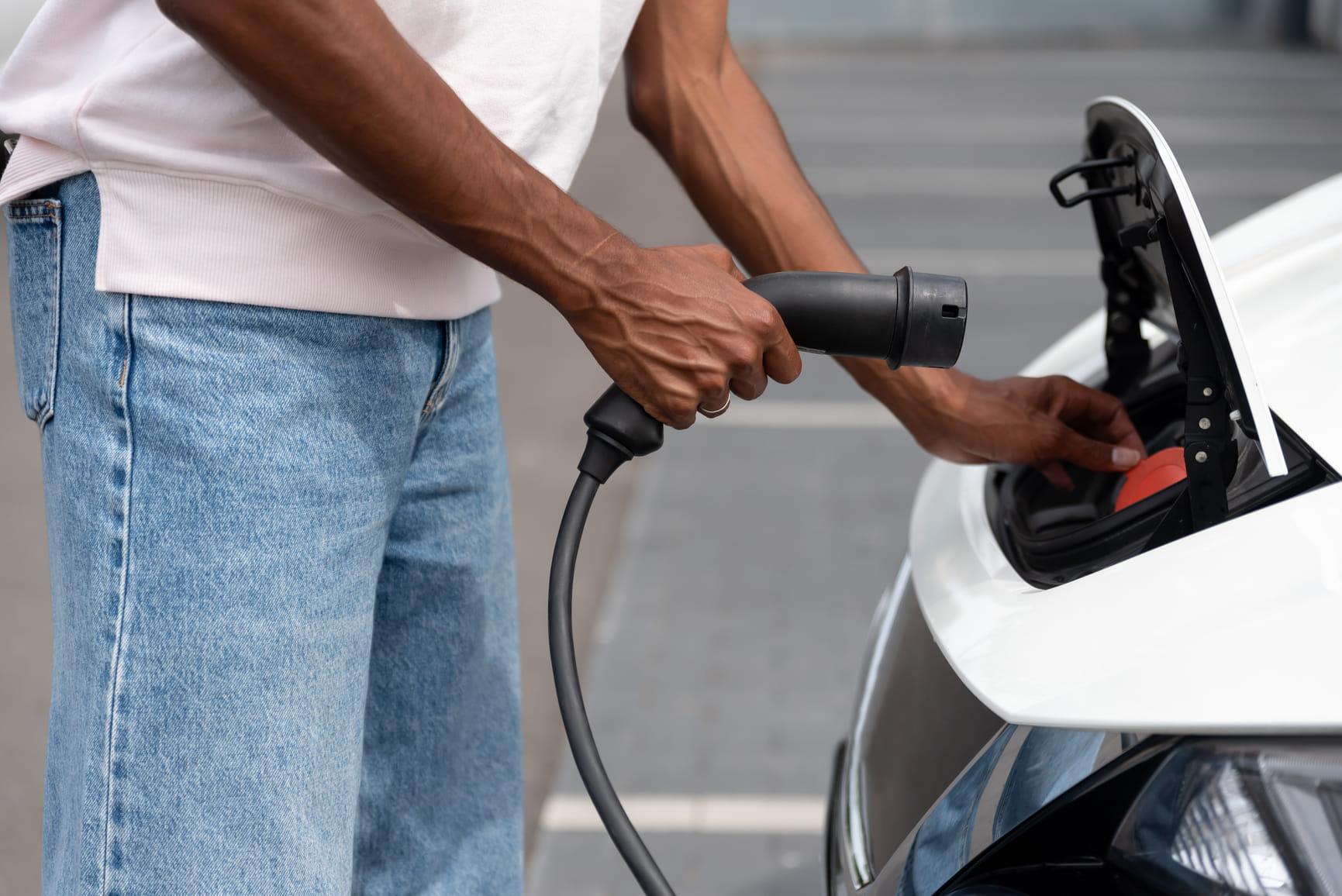 Man sluit laadkabel aan op een elektrische auto.