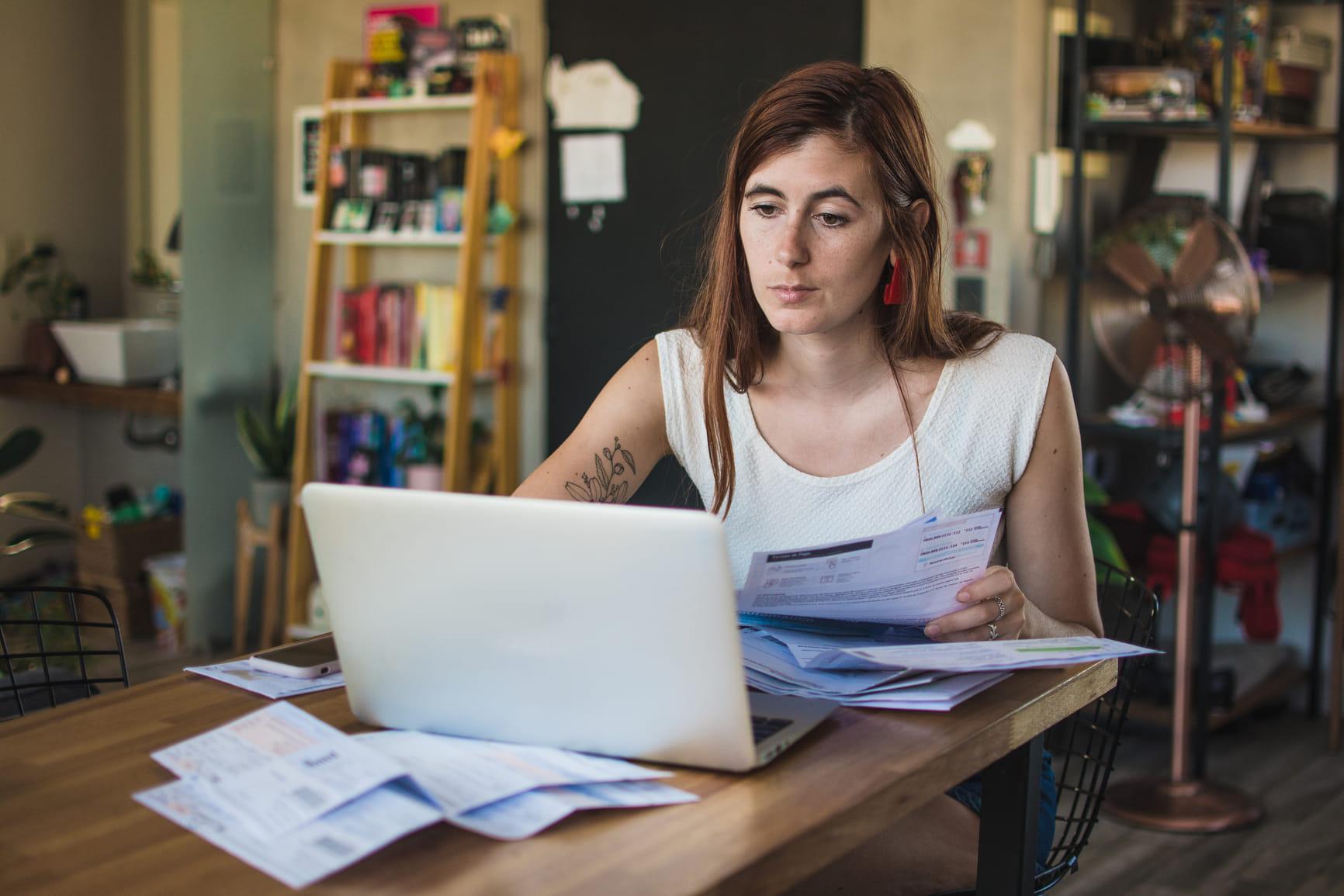 Vrouw zit achter een laptop en gaat door alle rekeningen.