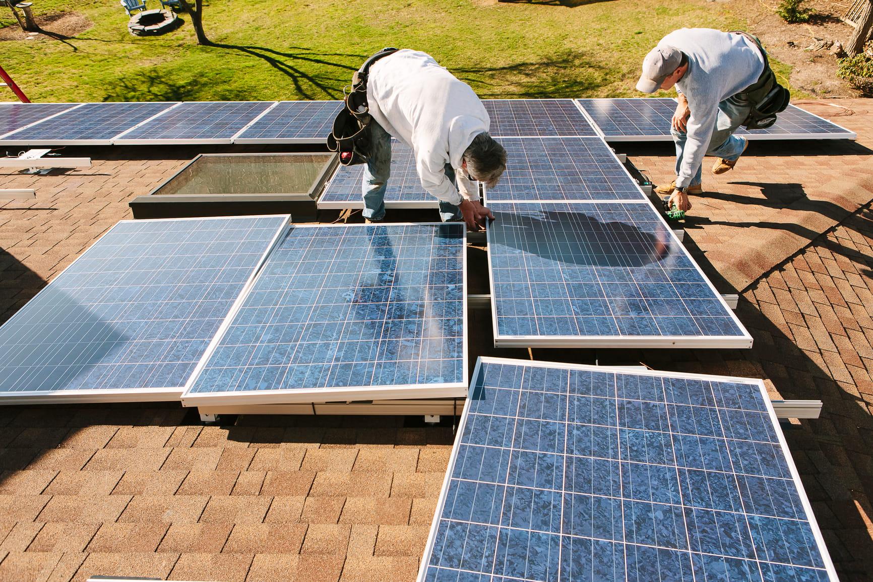 Twee mannen leggen zonnepanelen klaar om te installeren.