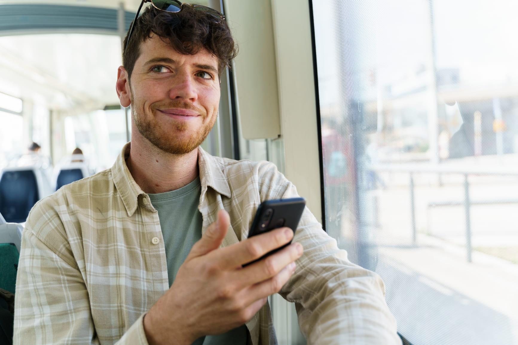 Man zit in een metro en kijkt op zijn telefoon.