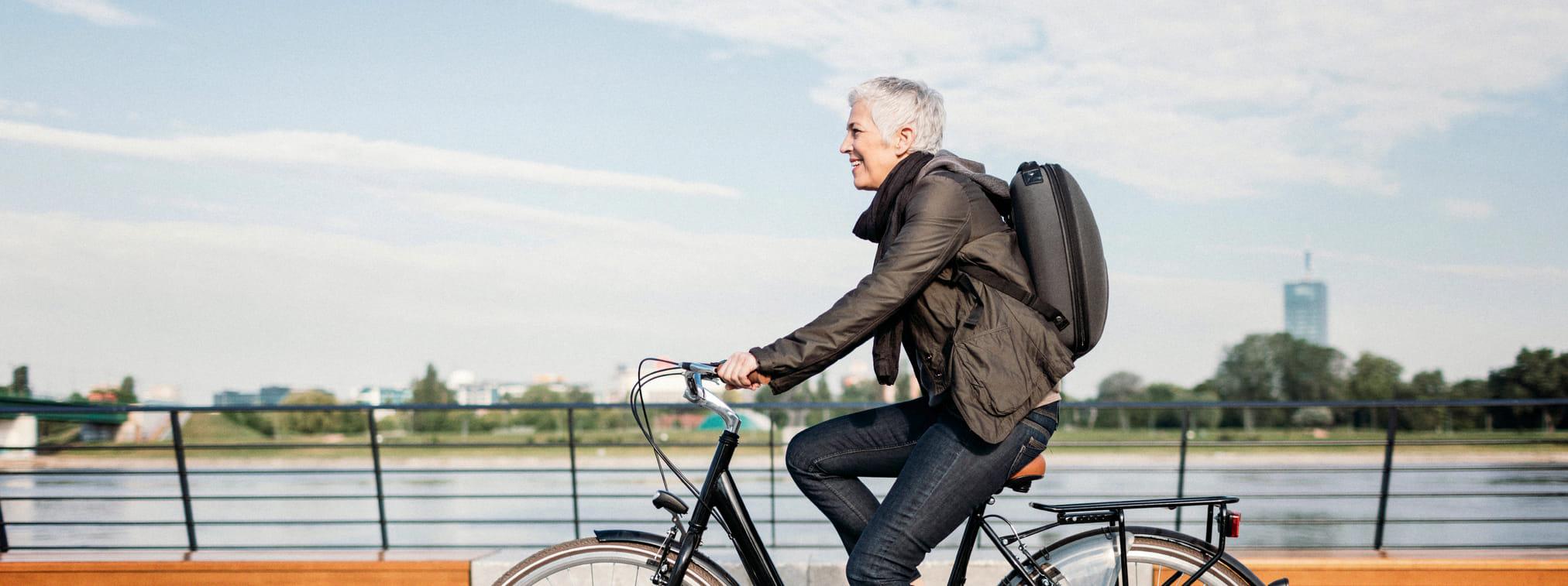 Een vrouw is op de fiets onderweg naar werk en fietst over een brug.
