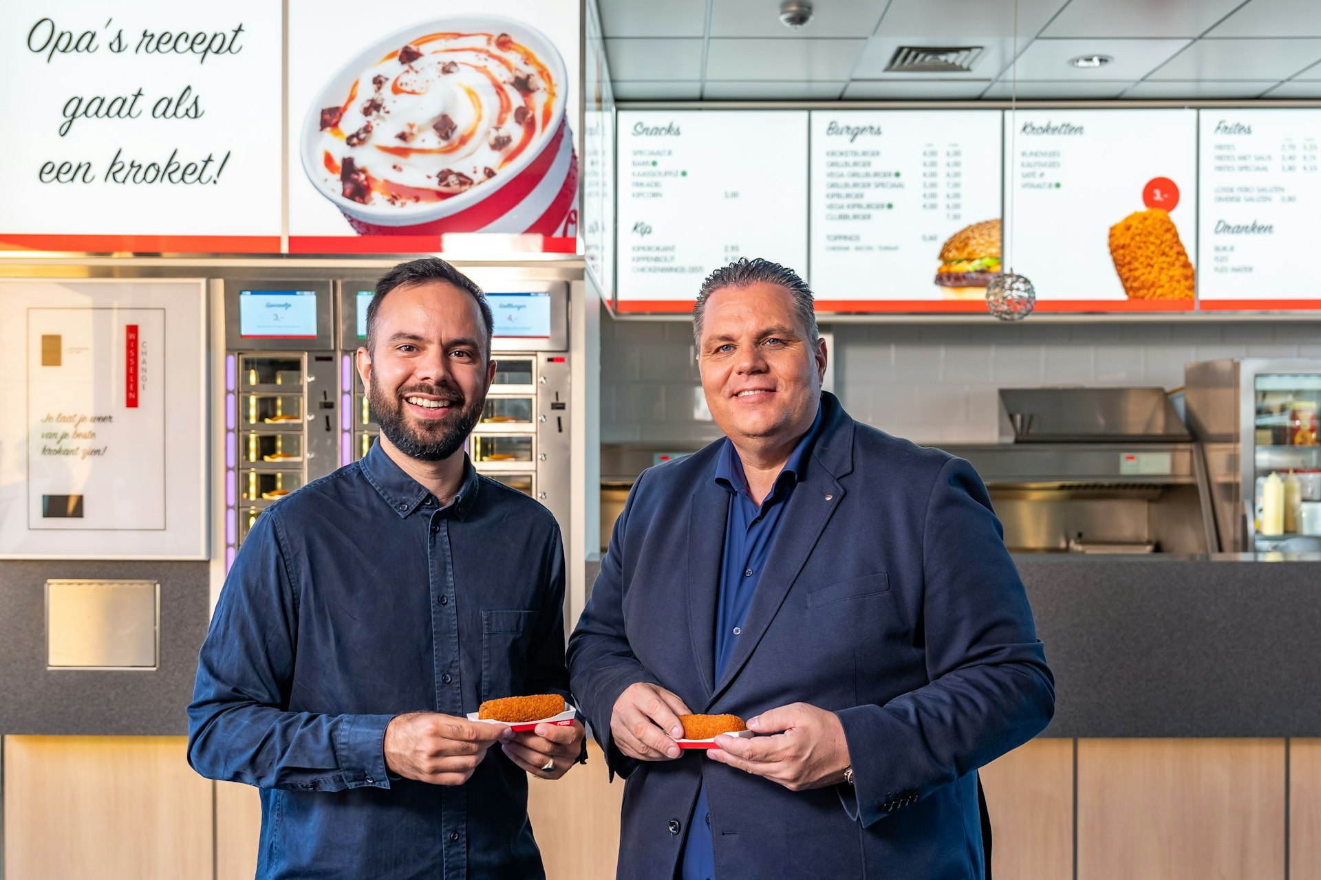 Foto van Dennis de Borst en Lukas Sloet in de FEBO. Ze houden allebei een kroket vast.