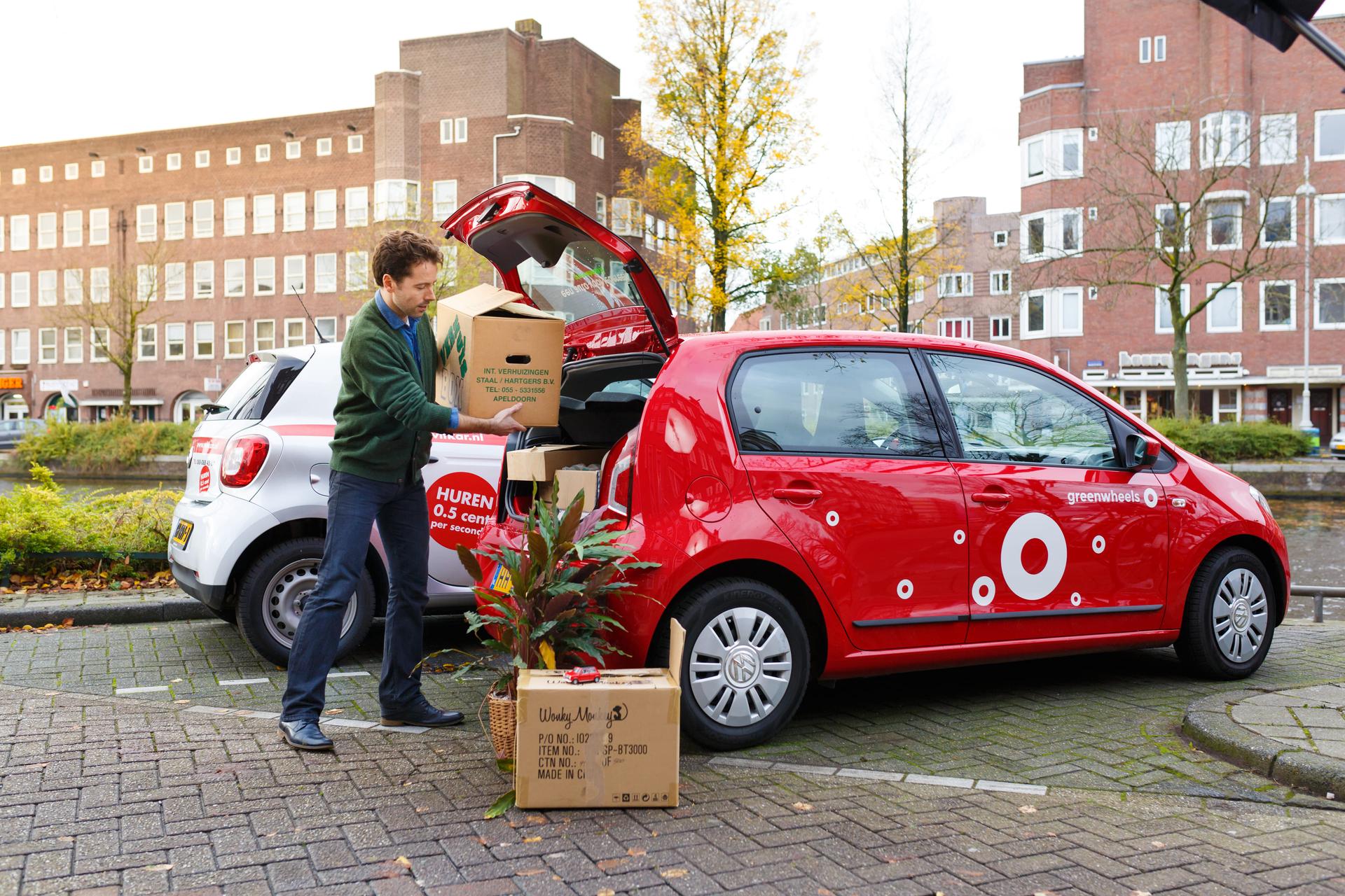 Man zet spullen in een deelauto.