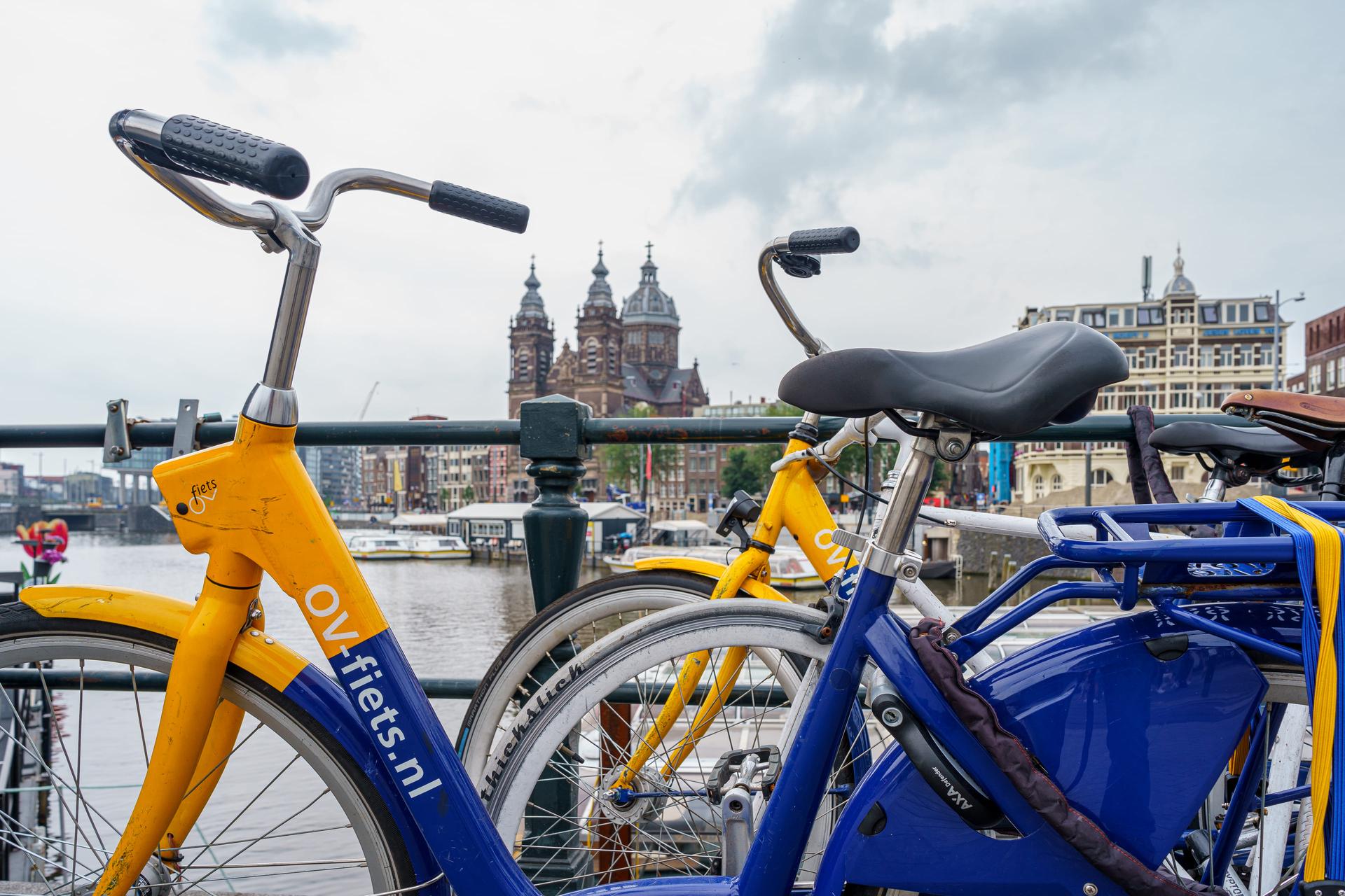 Foto van twee OV-fietsen die aan de reling van een brug staan geparkeerd.