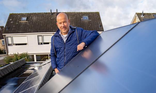 Foto van Alex Nijland die poseert naast een zonnepaneel.