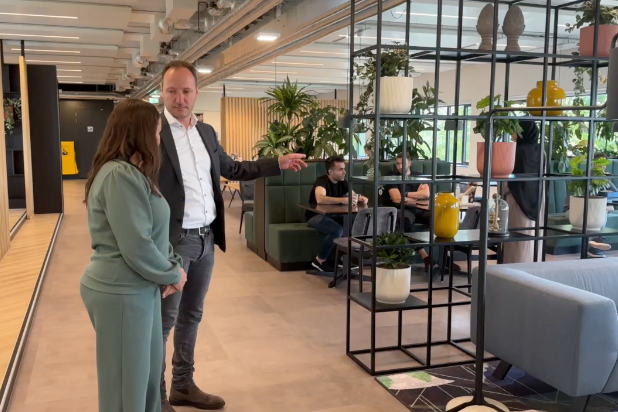 Martijn van Rijt laat de werkplekomgeving binnen de Rijksoverheid zien. Het is een open ruimte met veel zitplekken en groen.