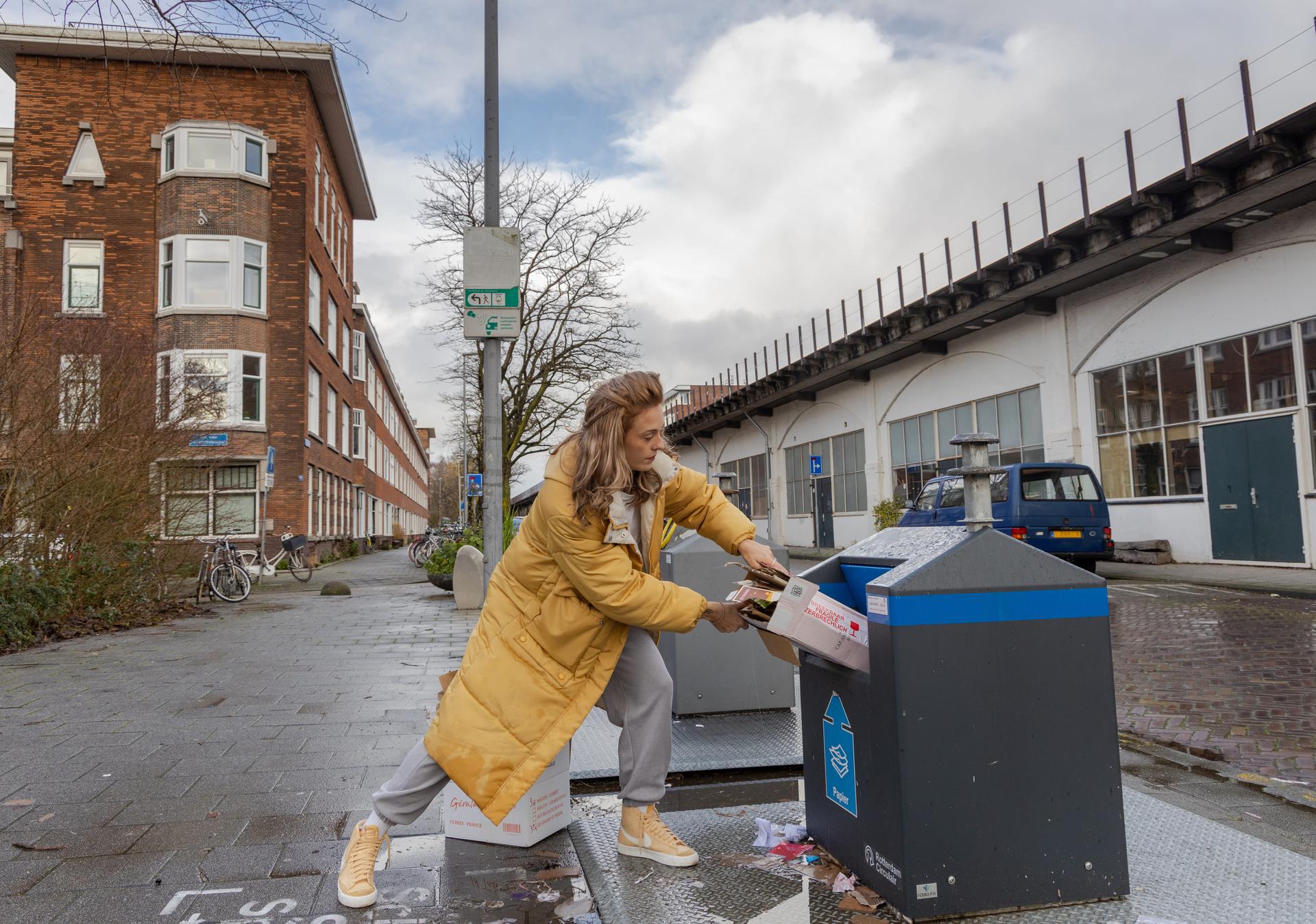 Vrouw gooit afval in een ondergrondse container.