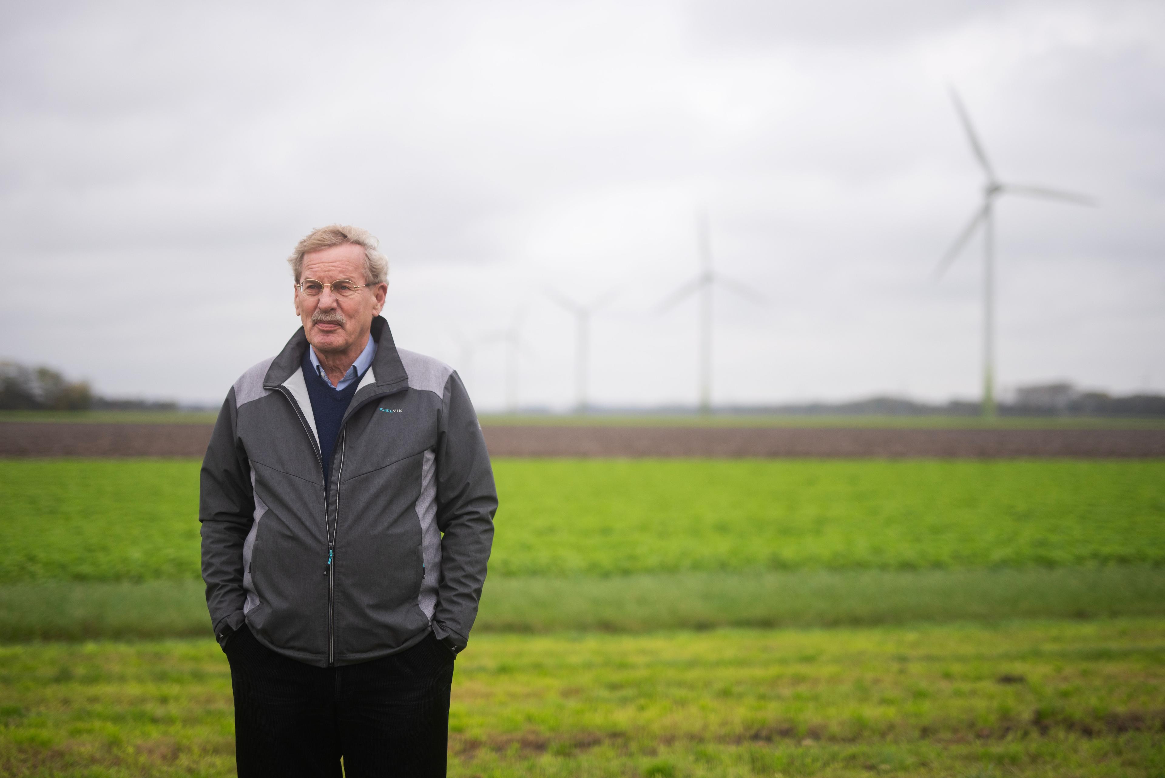 Meer staat op een grasveld in Zeewolde, met achter zich een windmolen.