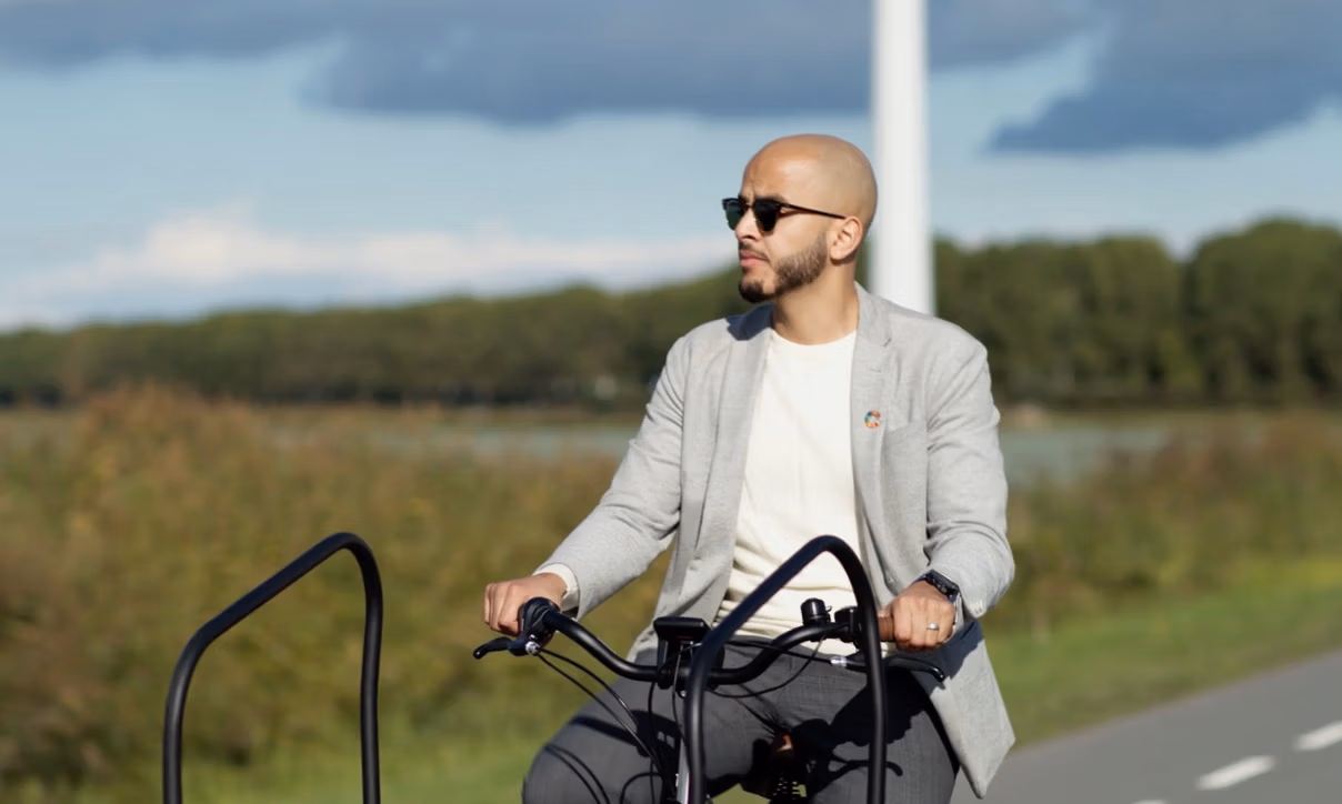 Ilyes fiets over een provinciale weg en heeft een zonnebril op.