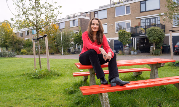 Judith van Loon die op een rood bankje op een grasveld zit.