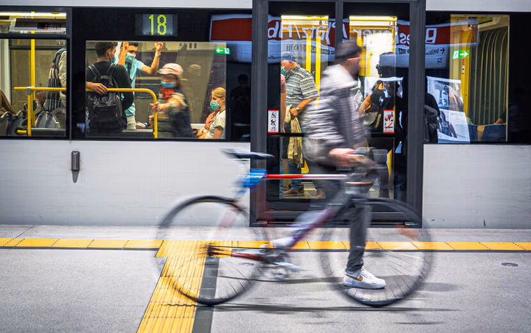 Foto van een metro. Daarvoor beweegt een man die een fiets meeneemt.