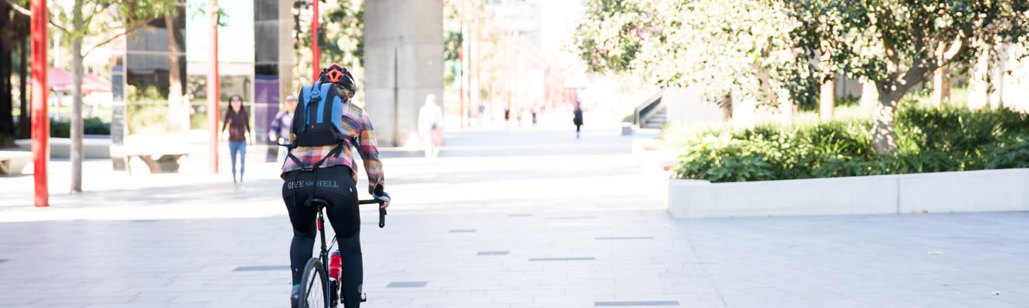 je ziet iemand van de achterkant die in de stad fietst.