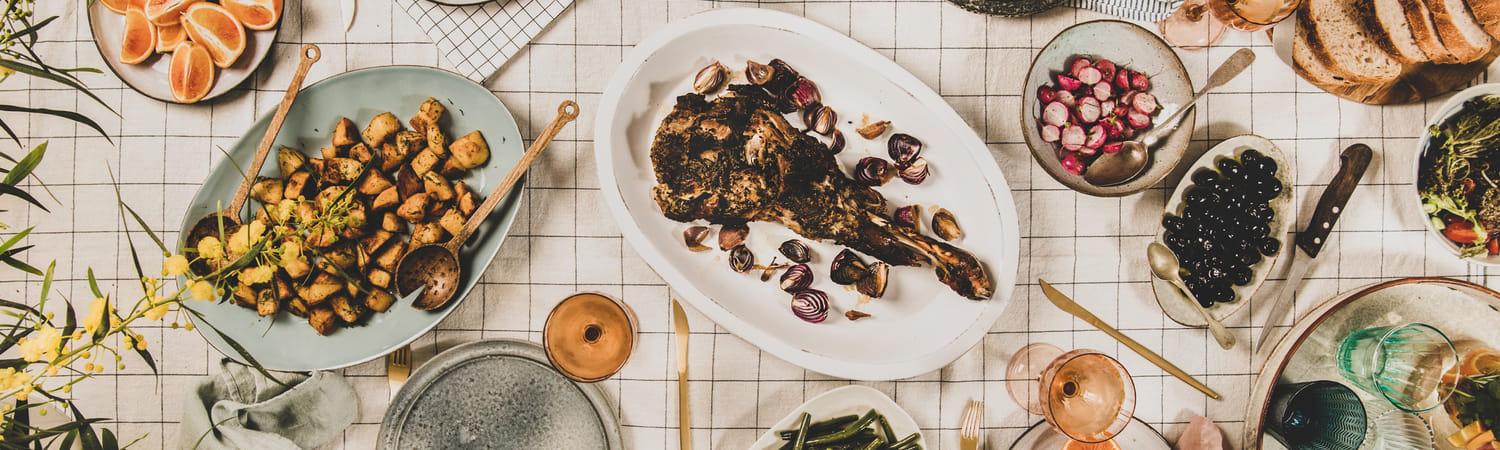 Gedekte eettafel met gezond eten zoals sinaasappels, radijsjes, olijven, sperzieboontjes en desembrood.