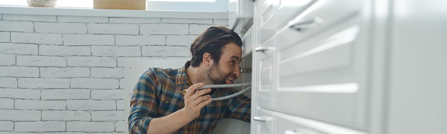 Jonge man repareert de gootsteen in huis met tweedehands materialen.