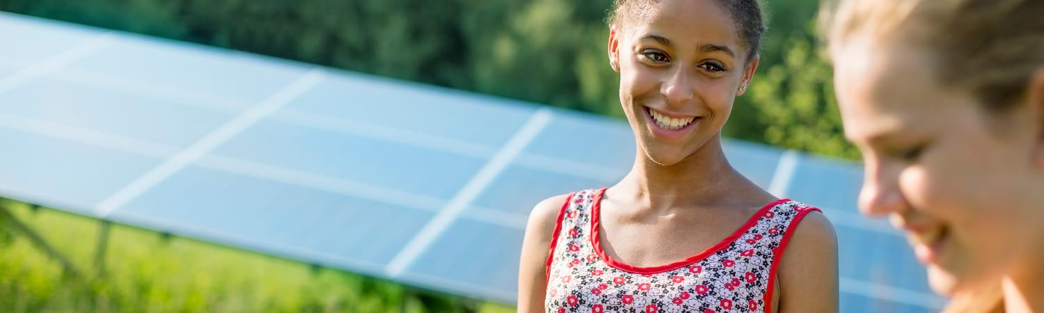 Twee meiden staan bij een veld met zonnepanelen.