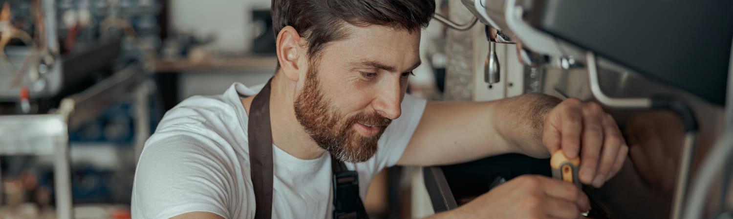 Monteur repareert een koffiemachine op kantoor.