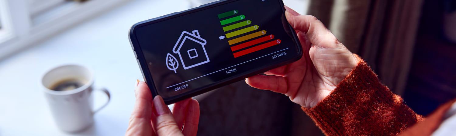 Vrouw houdt een een slimme energiemeter vast om te zien welk energielabel haar huis heeft.