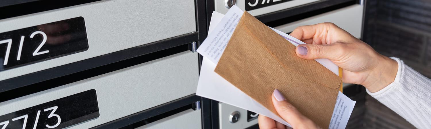 Persoon pakt brieven uit de brievenbus.