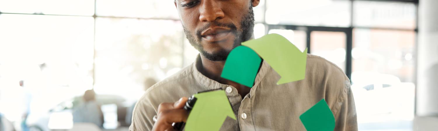 Man tekent een duurzaamheidslogo op een glazen wand op kantoor.