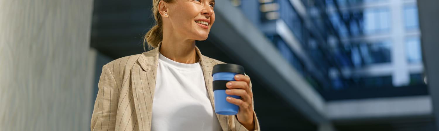 Vrouw houdt een herbruikbare koffiebeker vast.