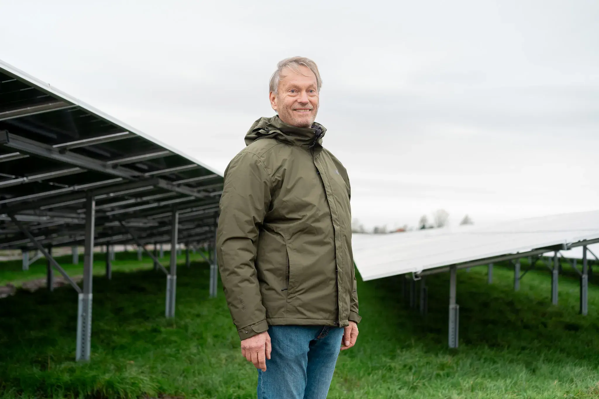 Man staat voor daken met zonnepanelen op het weiland.