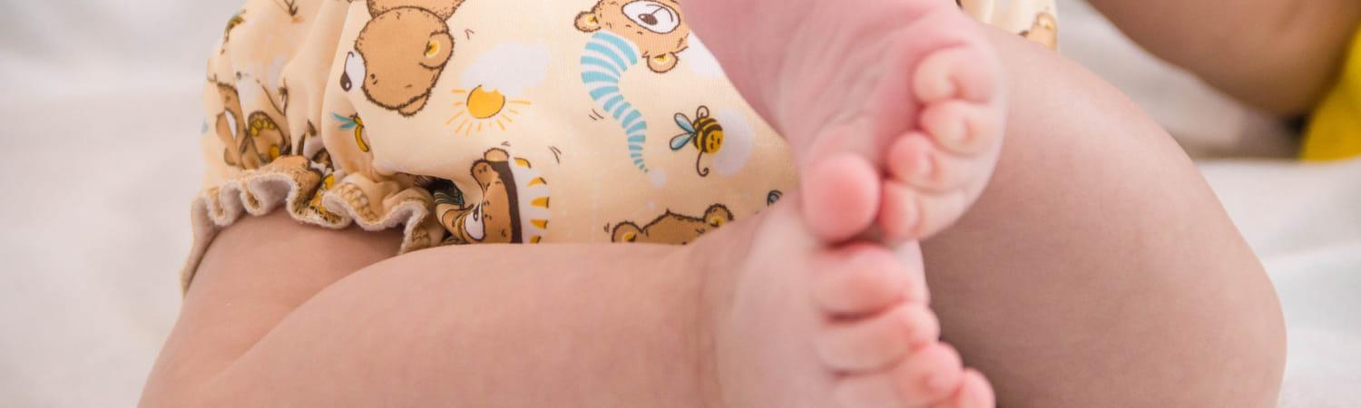 Baby met een vrolijke wasbare luier om.