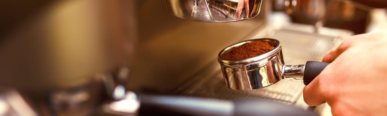 Een hand plaatst de hendel met koffie in de koffiemachine op kantoor.