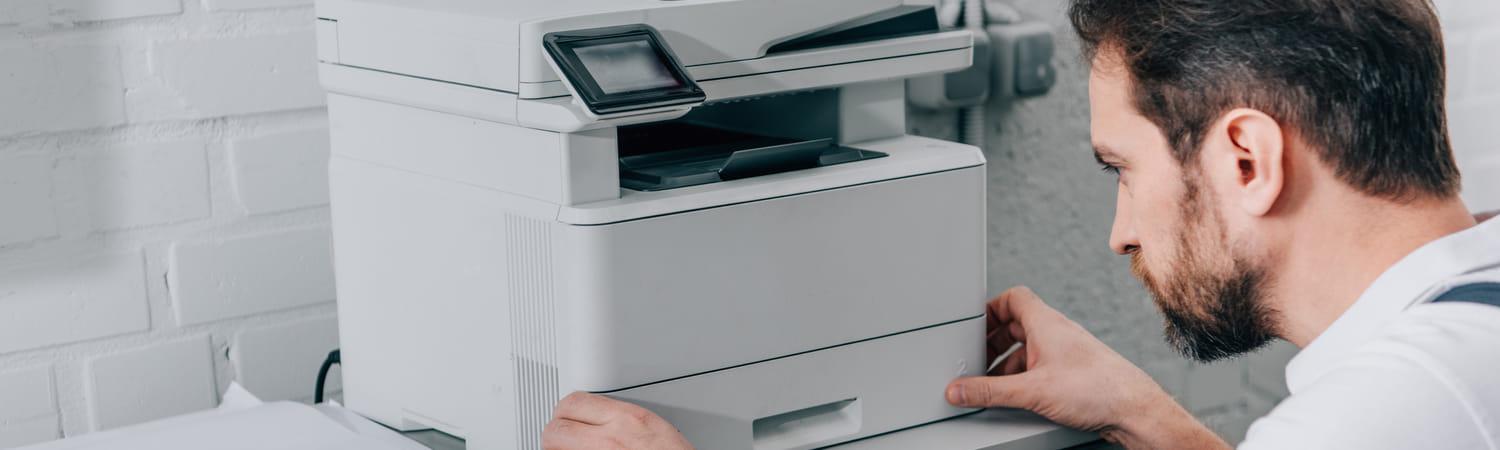 Een monteur repareert een printer op kantoor.