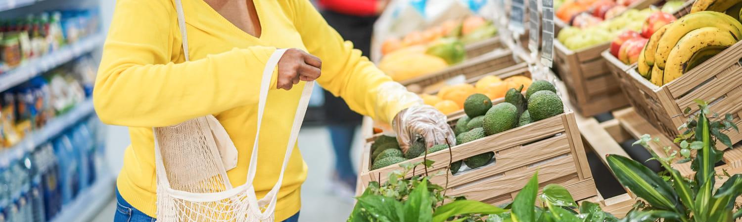 Vrouw koopt groenten in de supermarkt en stopt die in haar tas.