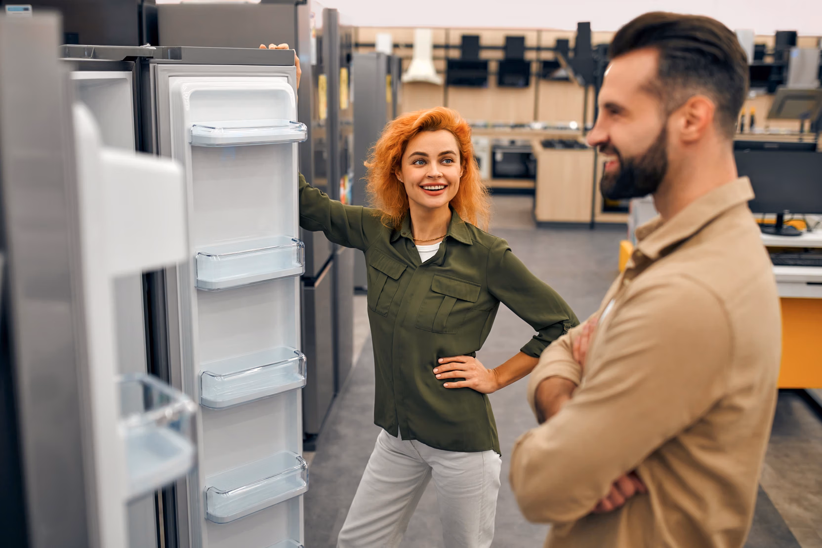 Vrouw laat een man een koelkast zien in de witgoedwinkel.