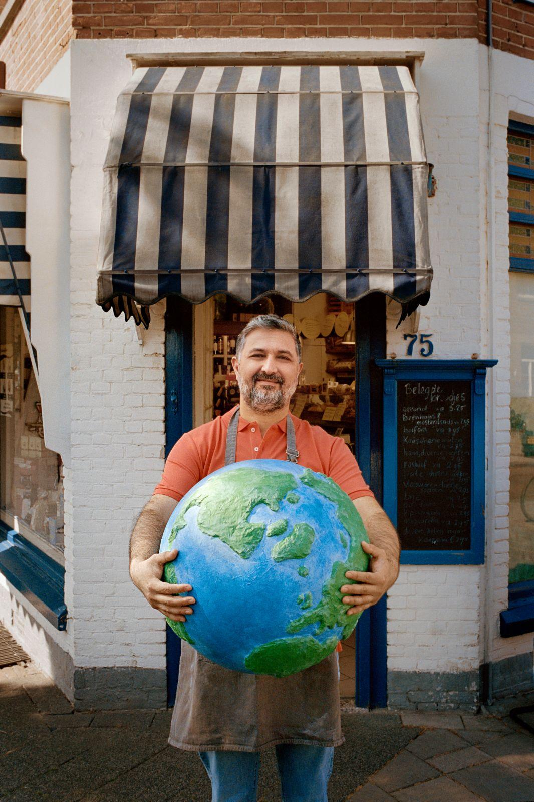 Een winkelier houdt een wereldbol vast.