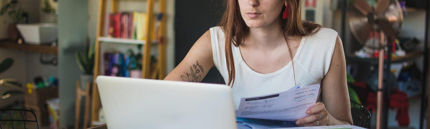 Vrouw zit achter een laptop en gaat door alle rekeningen.