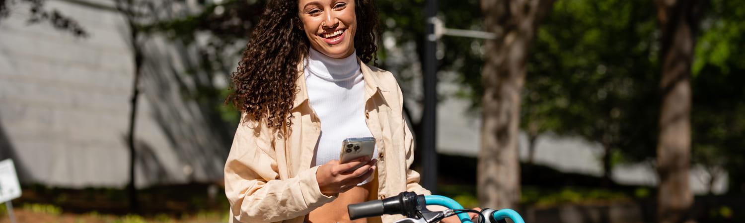 Vrouw houdt deel-bakfiets vast en lacht.