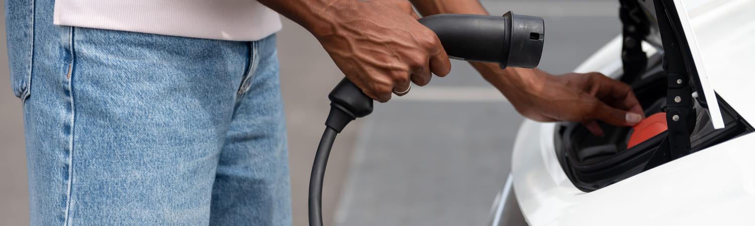 Man sluit laadkabel aan op een elektrische auto.