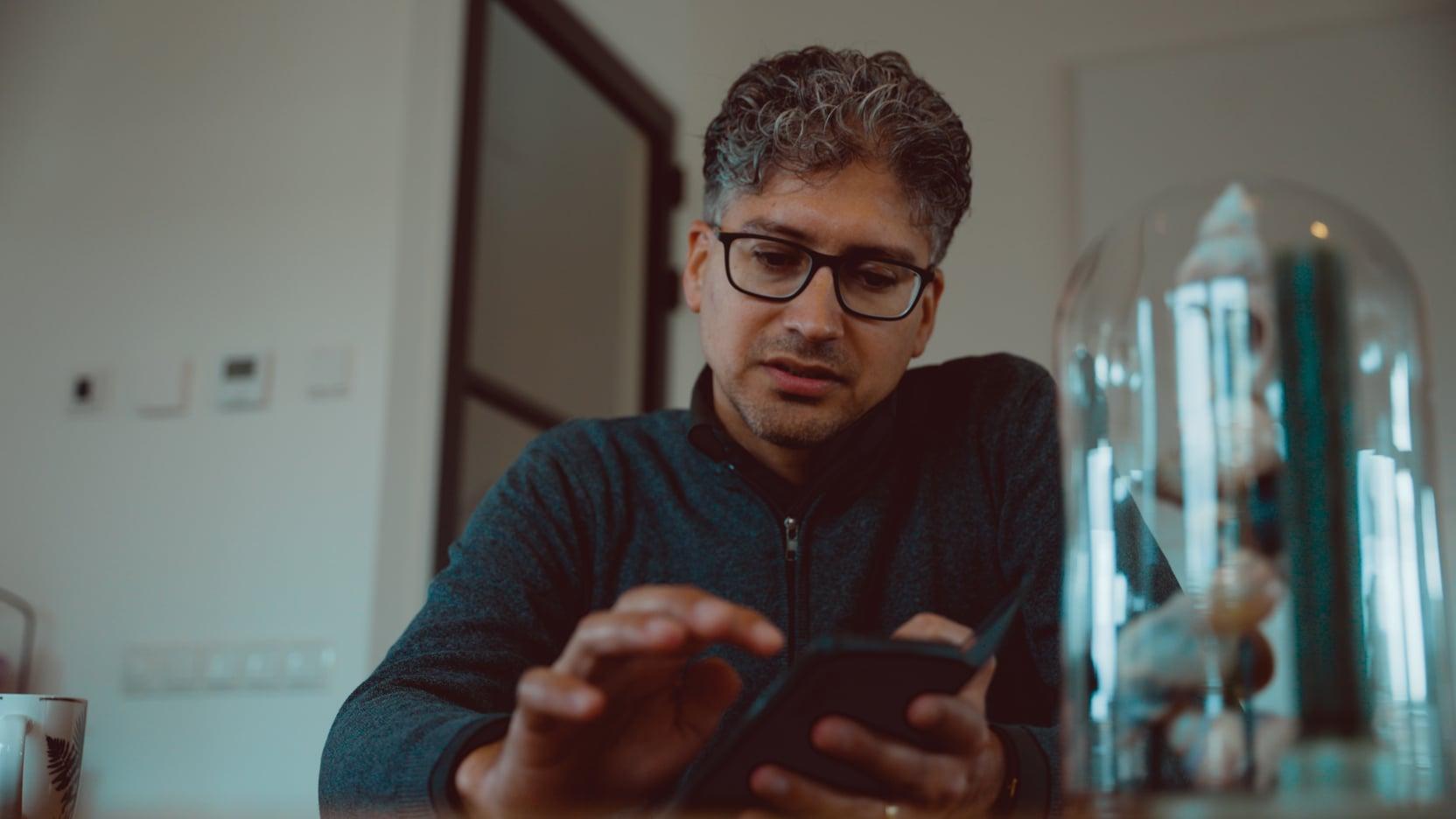 Buurtbewoner van de woonwijk Hooghkamer kijkt op zijn telefoon.