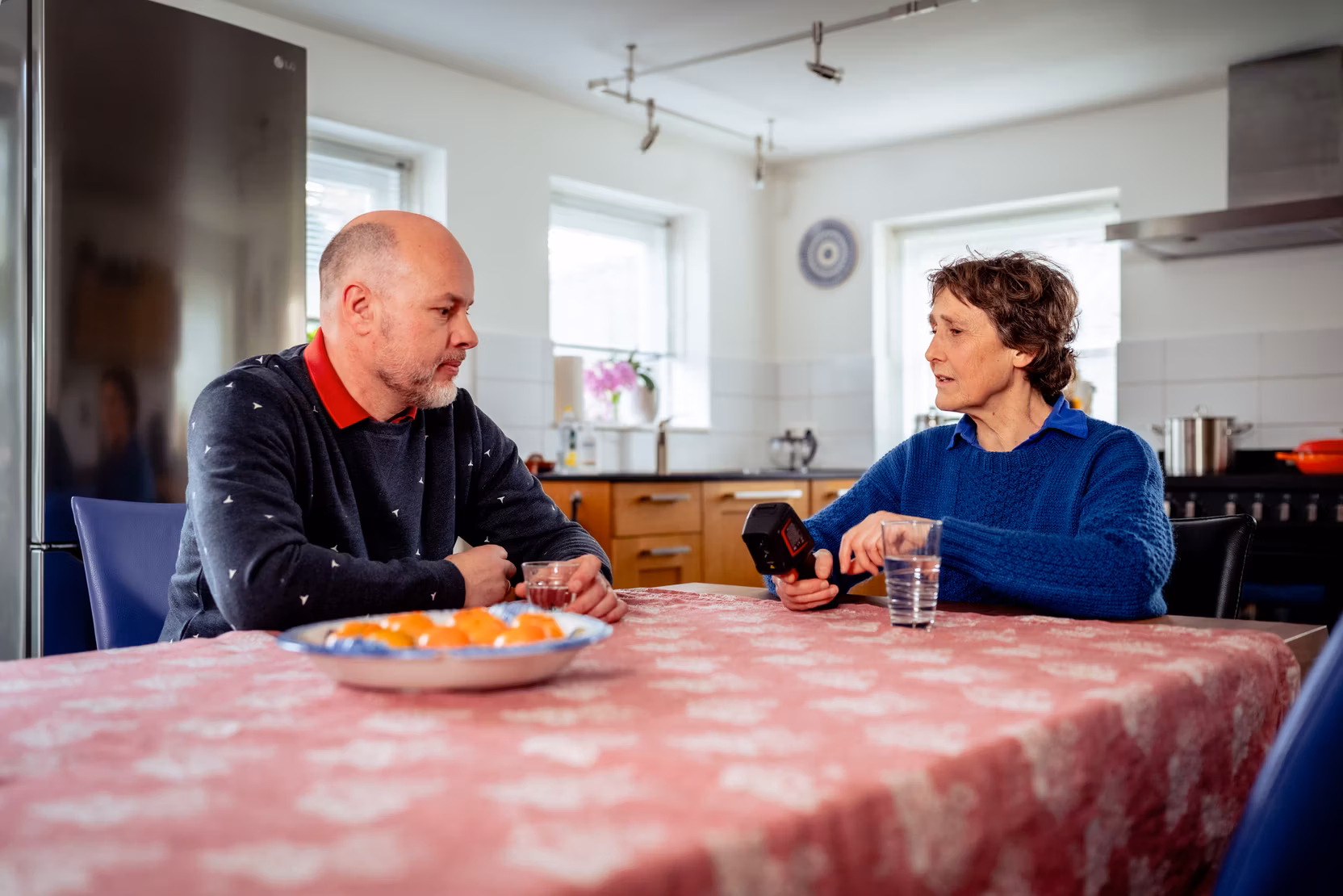 Annet Stomph zit aan de keukentafel met een man en laat de warmtecamera zien.