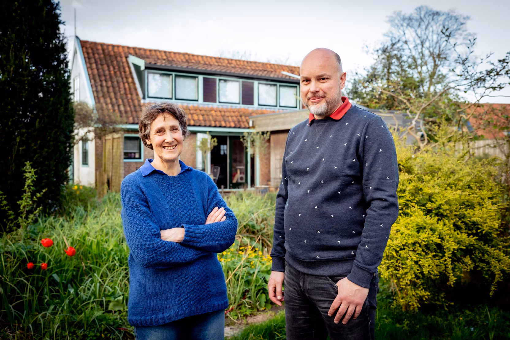 Annet Stomph en een buurtbewoner staan voor een huis.