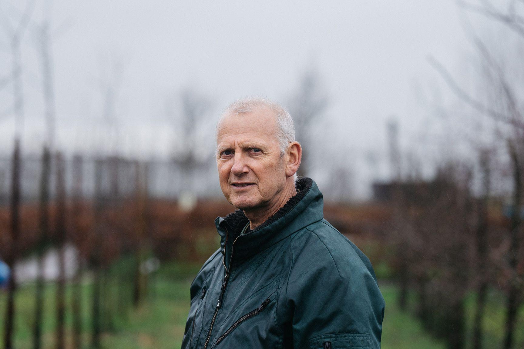 Portret van Jan de Boer, een fruitteler die voor zijn veld staat.